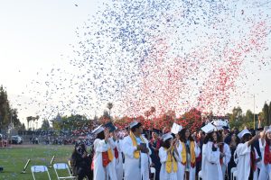After the graduated Class of 2022 turn their tassels from right to left, they are filled with emotions as they are rained on with colored confetti of red and blue.