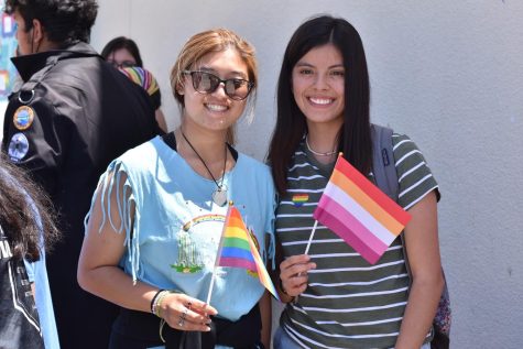 Seniors Thienly Nguyen and Kytzia Flores hold up LGBTQ+ pride flags at a Pride Rally, organized by the Acceptance club. 