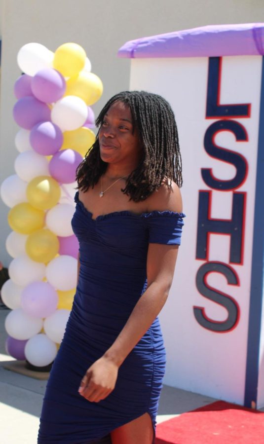 With a smile, junior Layani Taylor walks down the red carpet in a navy blue dress.  
