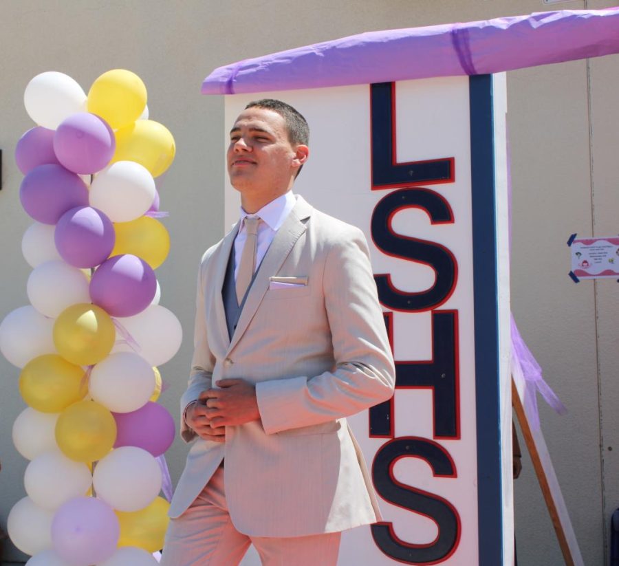Quentin Martins, senior, holds his beige suit while walking down the red carpet. 